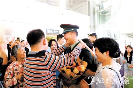 身著軍裝的返鄉(xiāng)退役士兵逐一出站，迎接他們的是鮮花與擁抱。